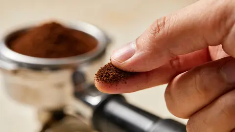 Frisch gemahlenes Espressopulver in einem Siebträger aus Edelstahl.